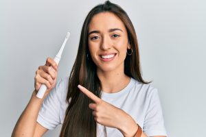 young woman pointing to electric toothbrush for better oral hygiene